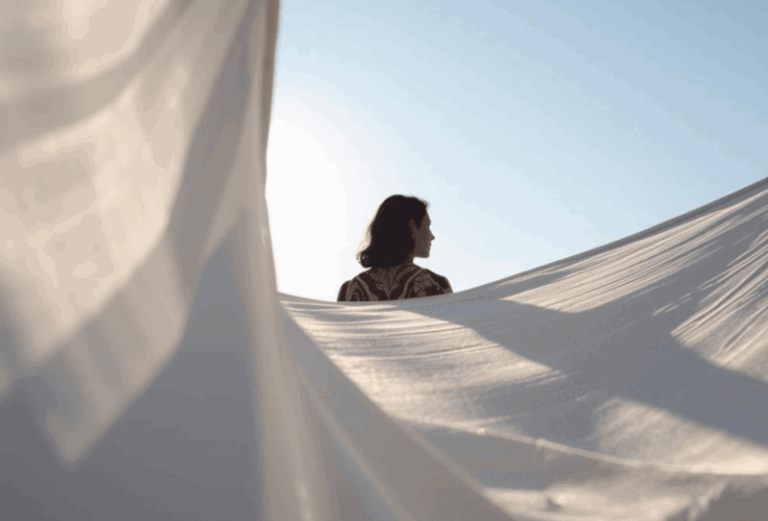Femme de dos et voiles blancs sur fond de ciel bleu